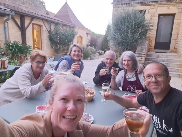Trip planners Clelia and Emilie with B&B hosts Eric and Nathalie and other guests outside eating dinner and drinking wine