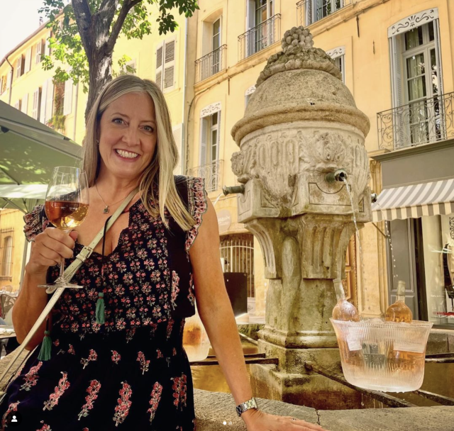 Traveler Martina standing next to a fountain in Aix-en-Provence with a grand of rose wine in her hand.