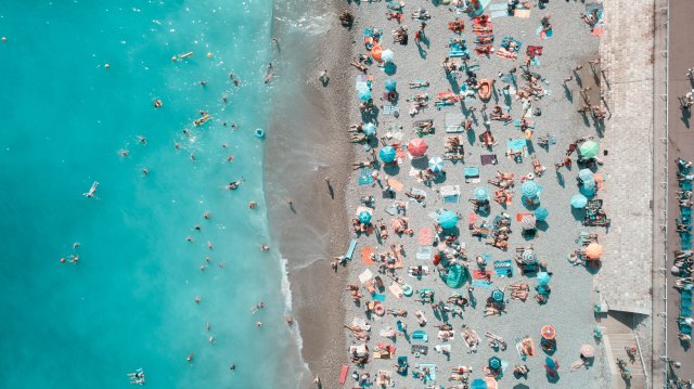 A birdseye view of a crowded beach in Nice with turquoise blue sea