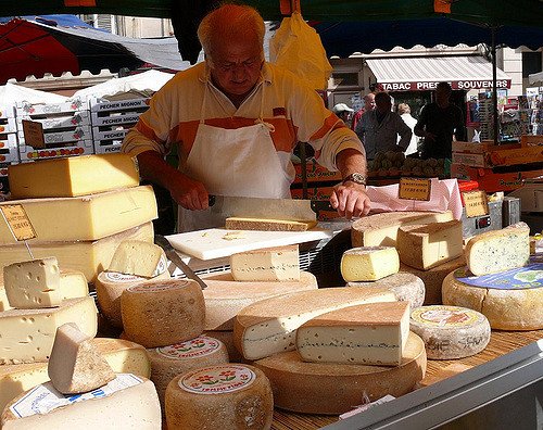 A man at a cheese stall in a market in France