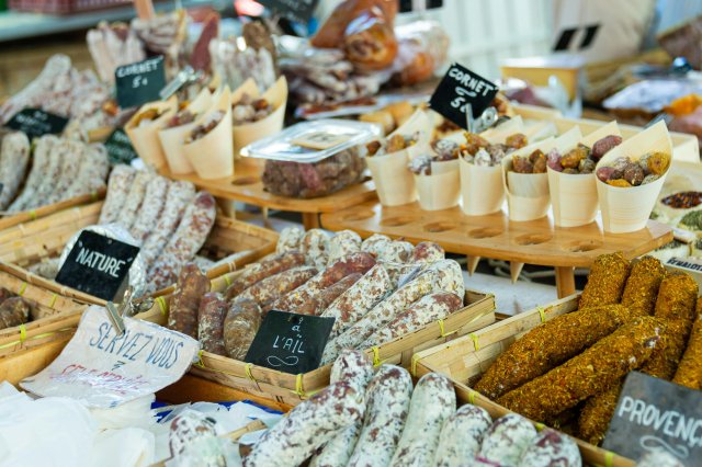 Baskets of fresh cheese, meats, nuts, and dried fruits at an open-air market in Aix-en-Provence, France